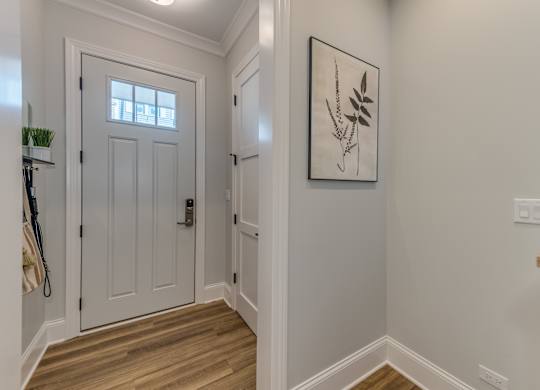 A modern builder grade entryway with front closet and stairs to the right.