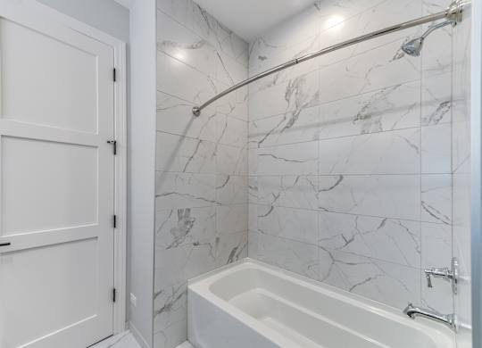 A modern builder grade bathroom with a marble tile shower and tub.