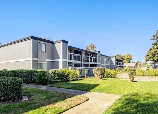 A modern building with a grey facade and a green lawn in front.
