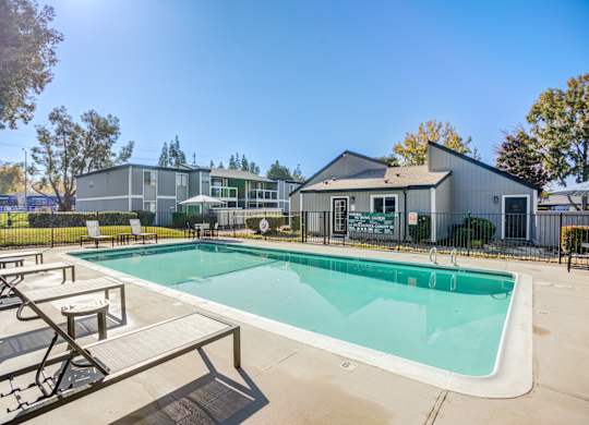A swimming pool with a bench and a building in the background.