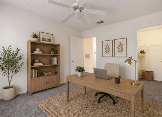 A room with a desk, chair, and a plant.
