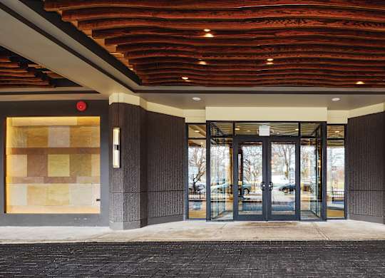 The image shows a building entrance with a red ceiling and glass doors.