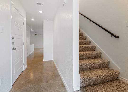 A hallway with a staircase and a white door.