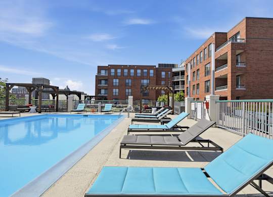 A rooftop pool with sun loungers and a building in the background.