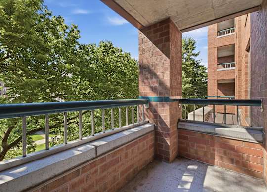 A balcony with a metal railing and a brick wall.