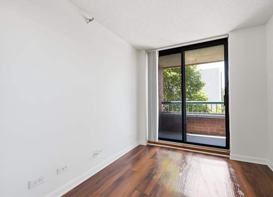 A den with wooden floors and a sliding glass door with a private balcony.