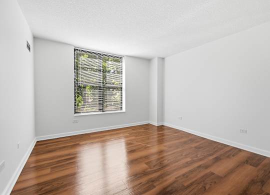 A bedroom with wooden flooring and window.