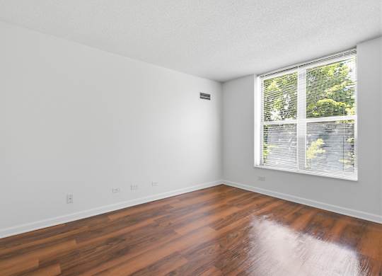 A bedroom with wooden flooring and window.