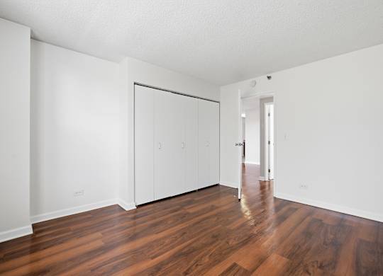 A bedroom with wooden flooring and closet.