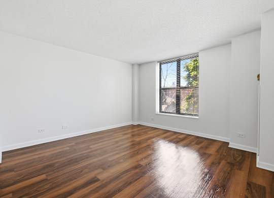 A bedroom with wooden flooring and window.