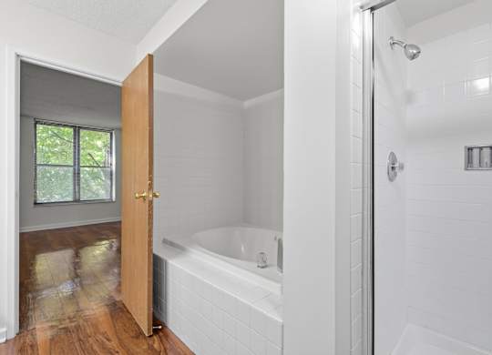 A white bathroom with standing glass shower and separate jacuzzi tub.