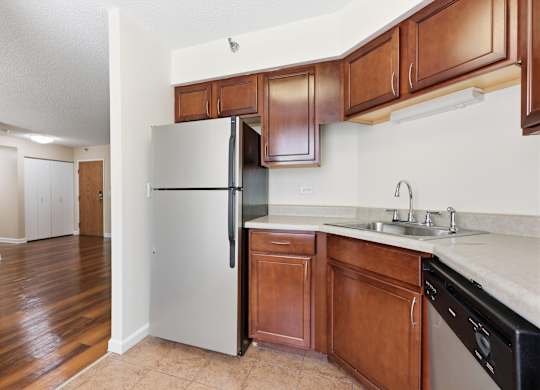 A kitchen with brown cabinets and a stainless steel appliances:  dishwasher and fridge.