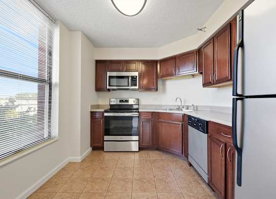 A kitchen with brown cabinets and a stainless steel appliances: microwave, stove, dishwasher, and fridge.
