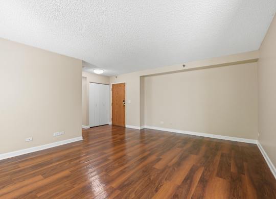 A living room with wooden floors and front hall closet.