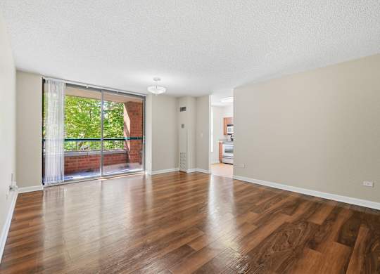 A living room with wooden floors and a sliding glass door leading to a private balcony.