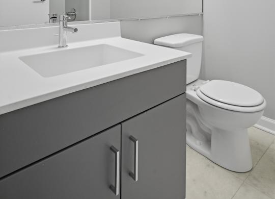 A white bathroom with a sink, toilet, and mirror.