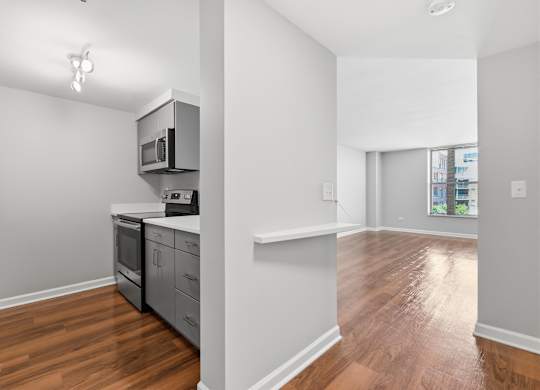 A renovated kitchen with a stainless steel refrigerator, microwave, oven, and 2-in-1 washer/dryer.