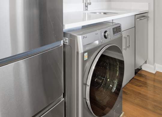 A renovated kitchen with a stainless steel refrigerator and 2-in-1 washer/dryer.