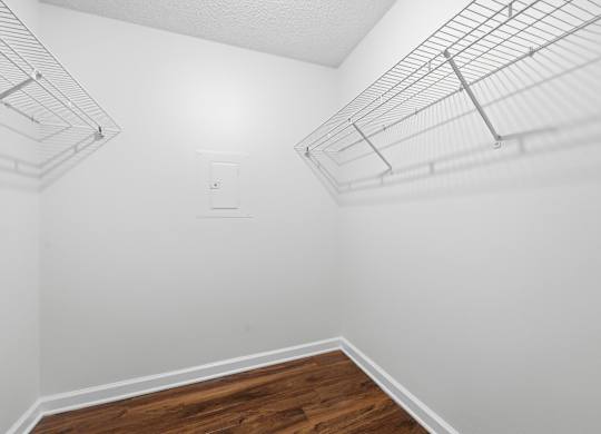 A white wall with a wooden floor and a metal shelf.