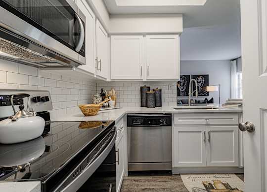 a kitchen with white cabinets and appliances and a black counter top