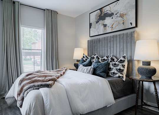 a bedroom with a large bed with pillows and a grey headboard