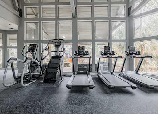 the gym at the monarch club has cardio equipment and a large window