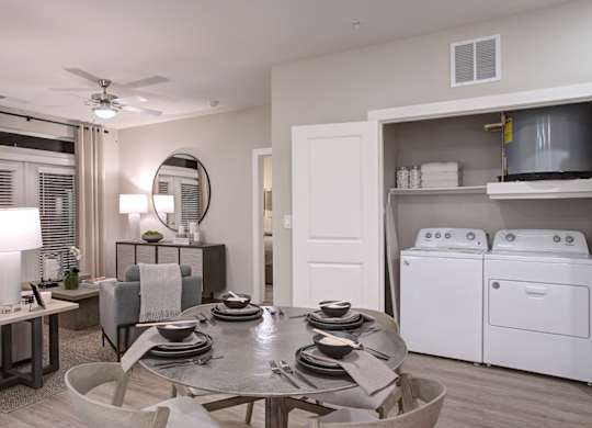 A modern dining room with a table set for four and a washer and dryer in the background.