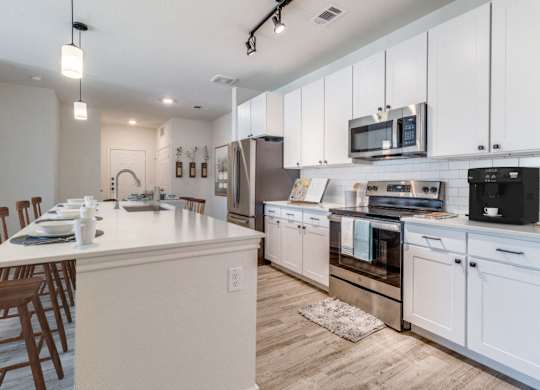 a large kitchen with white cabinets and stainless steel appliances