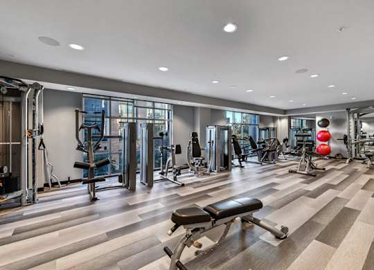 A gym with a variety of equipment including treadmills, weights, and exercise machines.