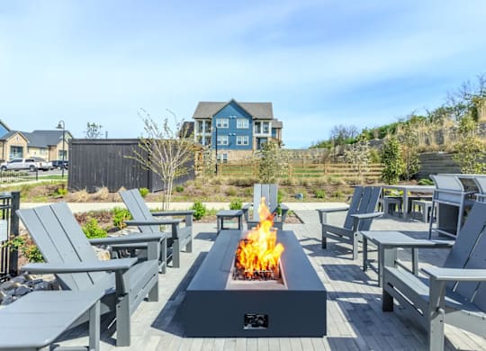 A fire pit in the middle of a patio surrounded by chairs.