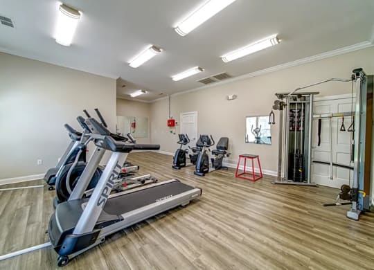 a gym with cardio equipment and weights on a wooden floor