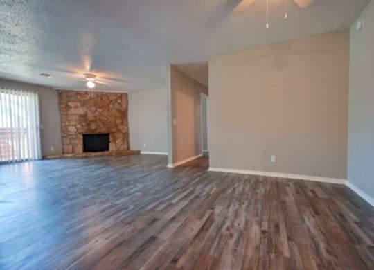 A room with wooden floors and a stone fireplace.
