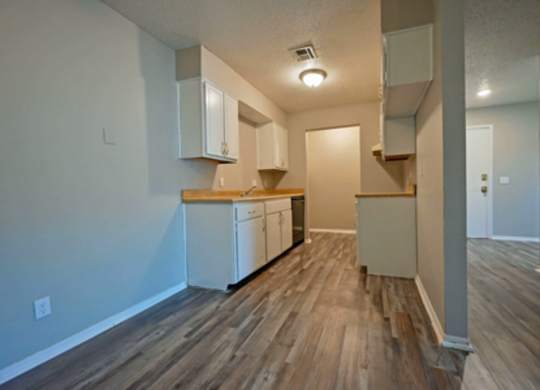 A kitchen with white cabinets and a wooden floor.