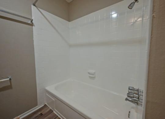 A white bathtub in a bathroom with a white shower curtain.