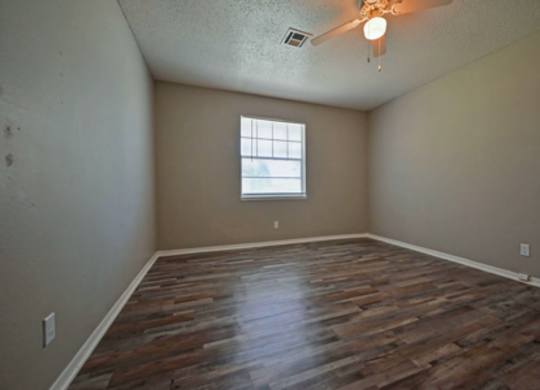 A room with wooden flooring and a window.