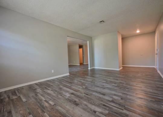 A room with wooden flooring and white walls.