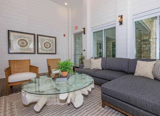A living room with a glass table and grey couch.