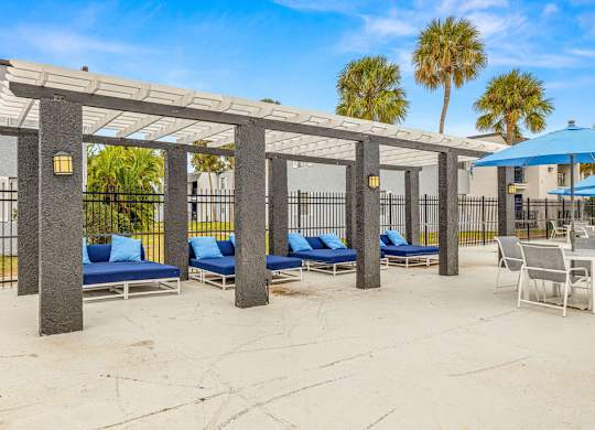 a covered patio with lounge chairs and umbrellas