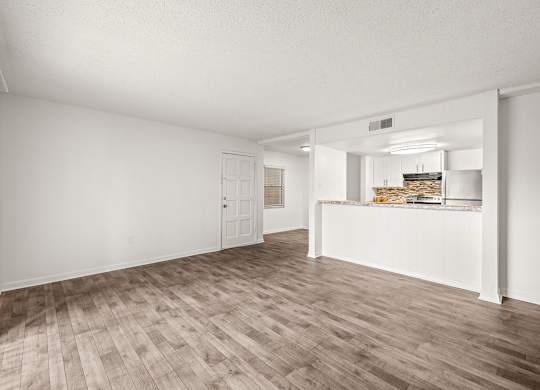 an empty living room and kitchen with wood flooring