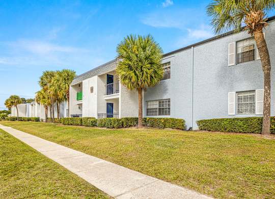 a white apartment building with palm trees in front of it