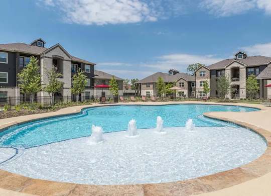 A large outdoor swimming pool with a fountain in the middle of it.