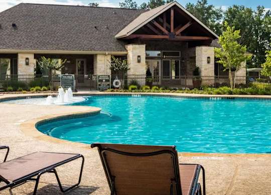 A pool with a chair and a house in the background.