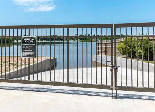 A metal gate with a sign on it in front of a body of water.