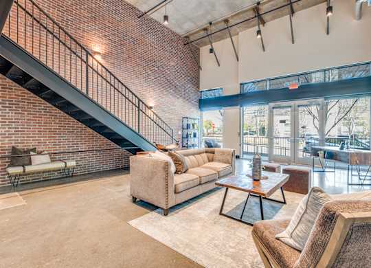 A living room with a couch, a coffee table, and a staircase.