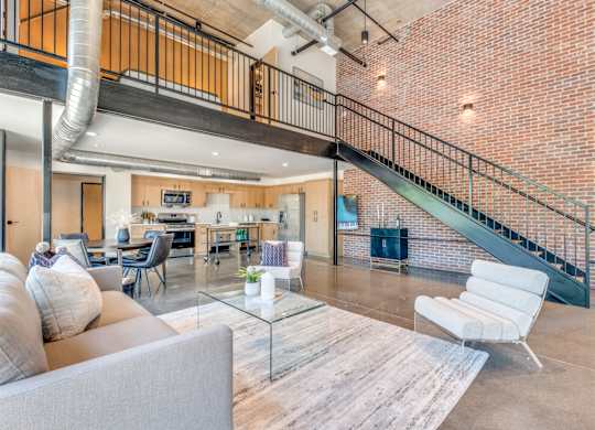 A living room with a grey couch and a glass coffee table.
