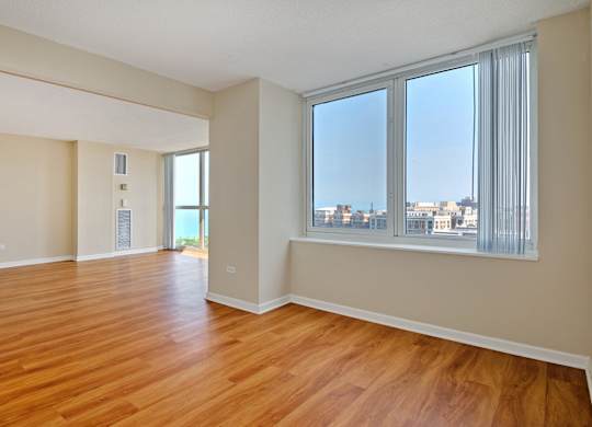 A room with wooden floors and a large window overlooking a cityscape.