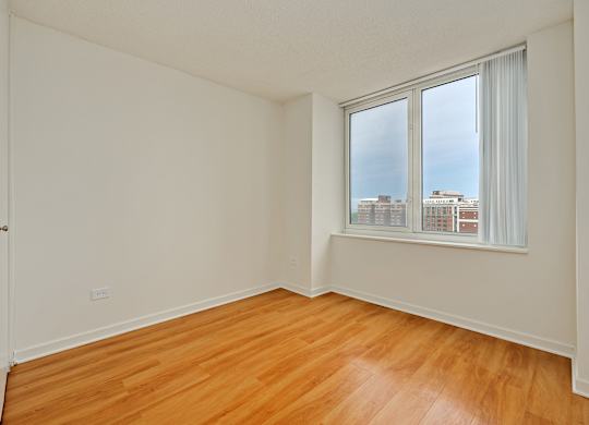 A room with wooden floors and a window overlooking a cityscape.