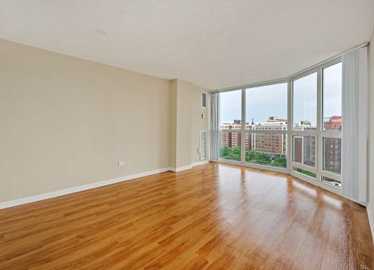 Empty room with wooden floors and large windows.