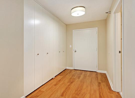 A hallway with a white door and wooden floors.