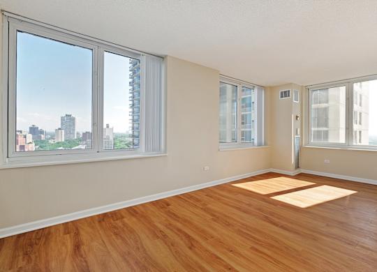A room with wooden floors and a view of the city through the windows.
